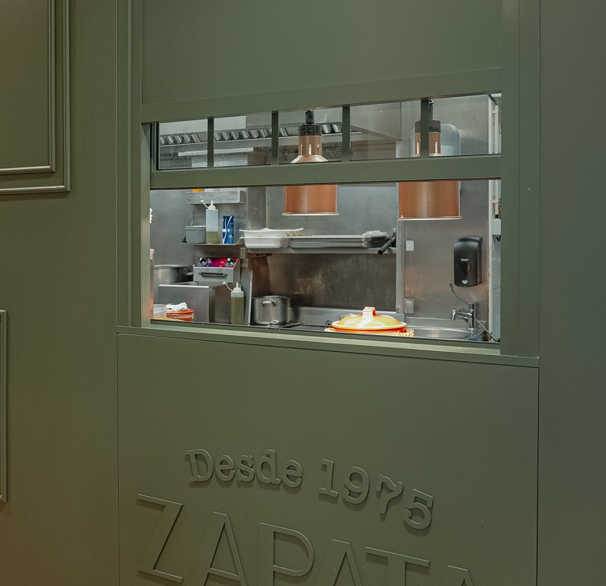Ventana de la cocina en la pared verde con el logotipo de Zapata