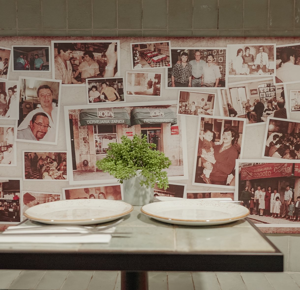 Mesa puesta junto a la pared de fotografías antiguas de las familias de la Cervejaria Zapata