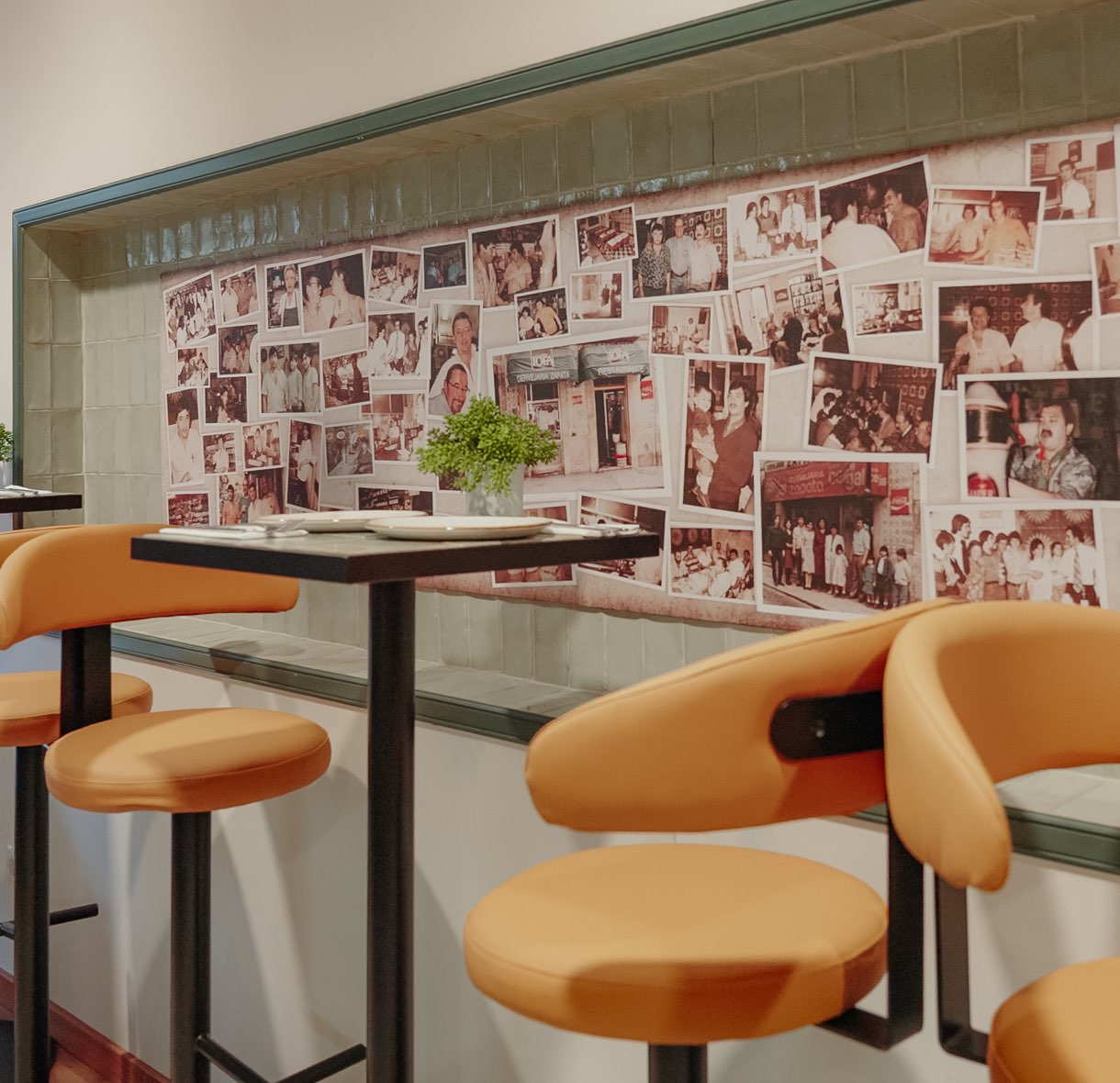 Taburetes altos junto a la pared de fotografías de las familias de la Cervejaria Zapata